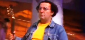 Homme Coluche, flou, guitare, scène, jean, lumière jaune.