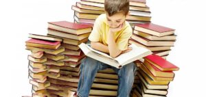 Enfant lisant parmi des piles de livres.